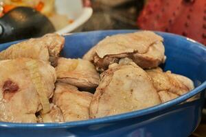 cocinero vierte pollo caldo desde cobre maceta dentro plato de pollo piernas foto