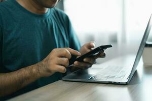 Man using smartphone after working with laptop on table, businessman using mobile phone to search or social media or shopping online. Business concept smart phone technology conversation conferrence. photo