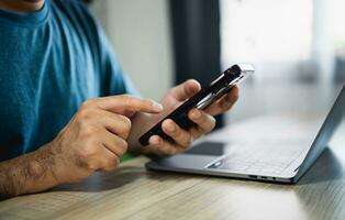 Man using smartphone after working with laptop on table, businessman using mobile phone to search or social media or shopping online. Business concept smart phone technology conversation conferrence. photo