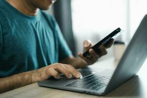 Man using smartphone after working with laptop on table, businessman using mobile phone to search or social media or shopping online. Business concept smart phone technology conversation conferrence. photo
