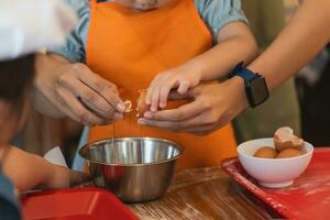 asiático niña aprendizaje a hornear pastel y agrietamiento huevos pastel ingredientes. horneando divertida. esta adorable bebé niña aprende a grieta huevos, mezcla ingredientes, y crear un delicioso pastel con asperja y Crema. foto