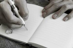 Hand writing white pen notebook with diamond ring photo