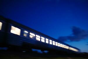 Illuminated train traveling past at night photo