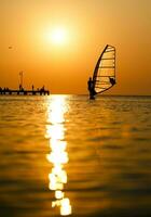 Silhouette of surfer at sunset passing by photo