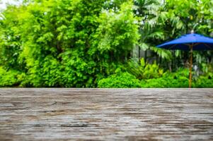 Wooden table on green garden backyard with umbrella photo