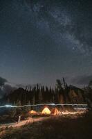 Camping tents with milky way in the night sky on campsite in autumn forest at national park photo