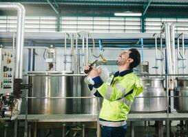 Successful of caucasian technician engineer man in safety uniform standing in pipeline, boiler tank laboratory at beverage processing plant photo