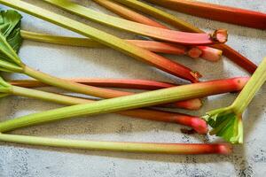 Fresh ripe green and red rhubarbs on a rustic grey and white table 2 photo