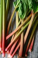 Fresh ripe green and red rhubarbs on a wood table photo