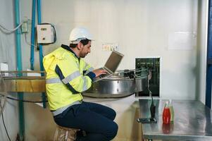 Caucasian engineer man in safety uniform checking and reporting quality a bottled fruit at conveyor belt in processing plant photo