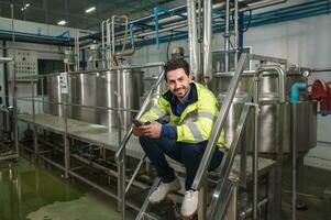 Caucasian engineer man using smartphone during break time on stair at processing plant photo