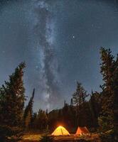 Camping tents with milky way in the night sky on campsite in autumn forest at national park photo