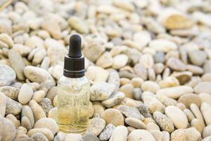 Cosmetic serum in a glass bottle with a pipette on stones photo