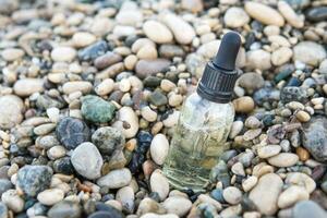 Cosmetic serum in a glass bottle with a pipette on stones photo