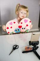 A blogger girl makes a felt craft for Valentine's Day in the shape of a heart. The concept of children's creativity and handmade. photo