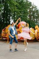 Happy young couple in love having fun in an amusement park and dancing photo