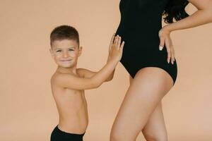 un pequeño chico niño sostiene su manos en su embarazada de la madre estómago foto