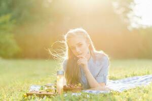 A pretty young woman is resting, lying on a blanket. Summer picnic in the park photo