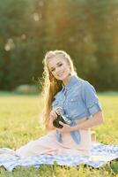 Young European tourist smiles happily using vintage camera in nature photo