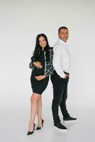 A happy young couple expecting a baby stands together on a gray background photo