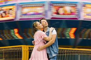 Happy couple in love enjoying each other in an amusement park and cuddling photo