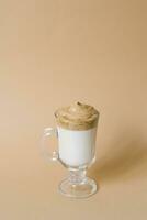 Beautiful dalgon drink coffee with foam in a transparent mug on a beige background photo