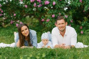 Happy Caucasian family with a young son relax in the park in spring or summer, lying on a blanket photo