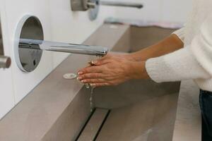 Women's hands under the water jet from the mixer. A middle-aged woman washes her hands in the bathroom photo