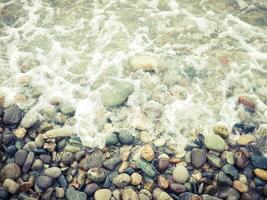 Seashore with pebbles and foam. photo