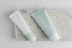 Cosmetic cream in tubes on marble tray, top view. Skin care products in plastic mockup squeeze tubes. photo