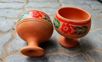 vacío hecho a mano arcilla vaso agua laico en madera estante, vaso con multiclor flor, arcilla vaso para Bebiendo agua ,fuente natural arcilla vidrio, marrón arcilla agua jarra foto