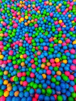 de colores el plastico pelotas son disperso. un montón de multicolor divertido globos.muchos vistoso el plastico pelotas en un niños' piscina de bolas a un patio de juegos. cerca arriba modelo foto