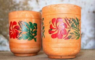 vacío hecho a mano arcilla vaso agua laico en madera estante, vaso con multiclor flor, arcilla vaso para Bebiendo agua ,fuente natural arcilla vidrio, marrón arcilla agua jarra foto