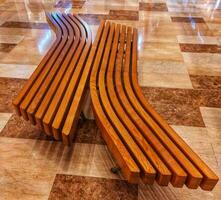 Wooden bench in the shopping mall. Recreation area in the shopping center with wooden benches,empty long wooden bench in the city square. Decoration.Wooden narrow planks background close up photo