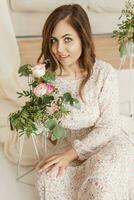 A brown-haired woman with long hair is having breakfast in a beautiful floral location. Spring portrait. photo