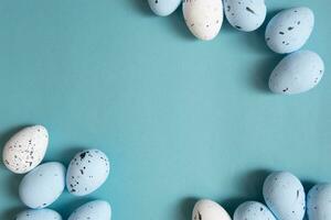 Easter background. Blue and white painted quail eggs on a blue background photo