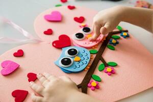 A blogger girl makes a felt craft for Valentine's Day in the shape of a heart. The concept of children's creativity and handmade. photo