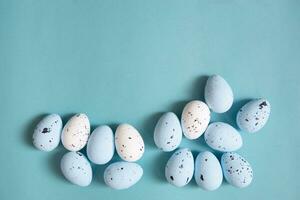 Easter background. Blue and white painted quail eggs on a blue background photo