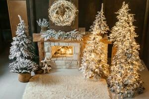 The interior of a room with a fireplace, Christmas trees with artificial snow and garlands, a blanket and a tray with hot drinks. The magical atmosphere of Christmas. photo