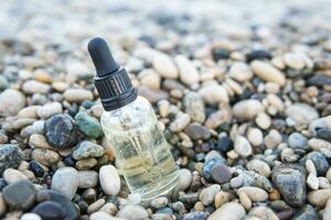 Cosmetic serum in a glass bottle with a pipette on stones photo