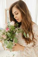 A brown-haired woman with long hair is having breakfast in a beautiful floral location. Spring portrait. photo