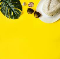 Beach accessories on the yellow background - sunglasses and striped hat. Summer is coming concept.Tropical leaves Monstera. Summer flat lay, top view. Space for text. photo