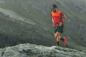 An athlete runs over boulders in the mountains photo