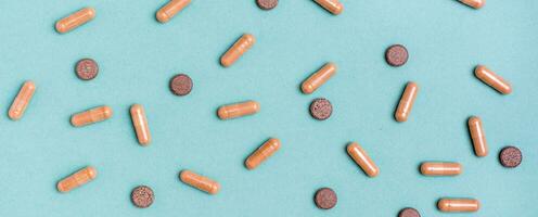 Abstract green background with herb capsules and pills. Alternative medicine. Top view. Web banner photo