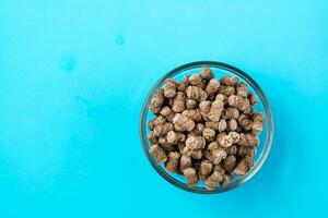 Fresh rye bran in a bowl on a blue background. Top view photo