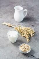 Oat milk in a cup, oatmeal and ears of corn on the table. Alternative to cow's milk. Healthy eating. Vertical view photo