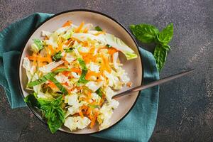 Close up of traditional cole slaw salad of cabbage, carrots and greens on a plate top view photo