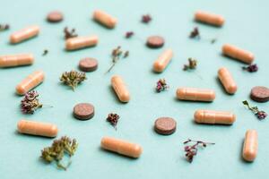 Abstract green background with capsules, pills and herbs. Alternative medicine. Selective focus photo