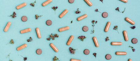 Abstract green background with capsules, pills and herbs. Alternative medicine. Top view. Web banner photo