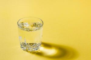 un solitario vaso de agua en un amarillo-gris paleta. soledad y autosuficiencia concepto. Copiar espacio foto